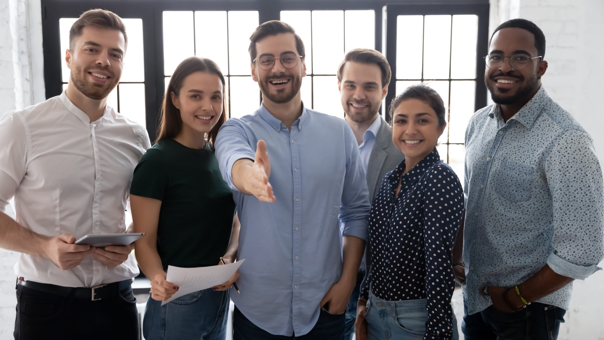 Millennial male leader stretch out his hand for handshake welcoming new employee invites newcomer to corporate team, group showing amity, human resources, boss greets clients express respect concept